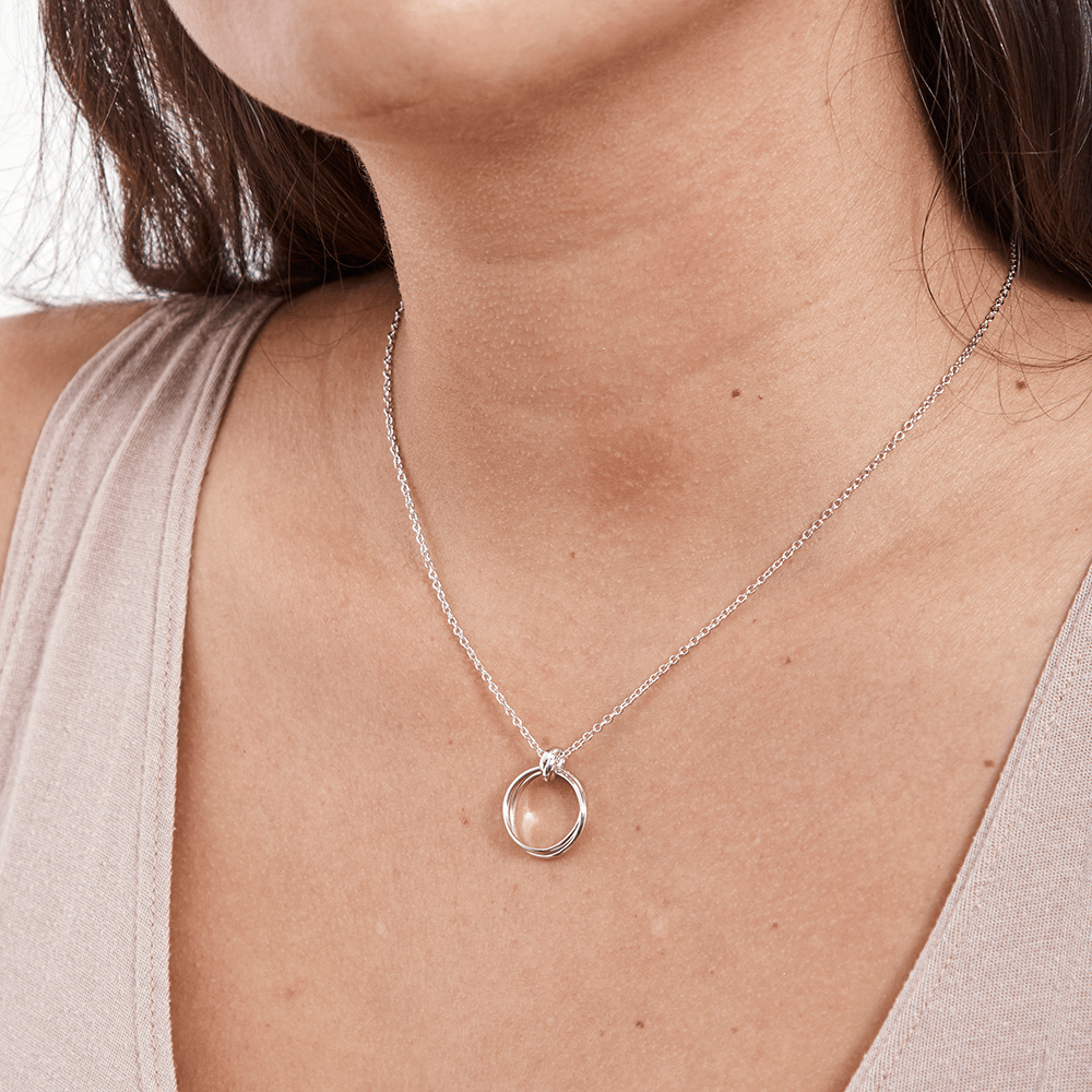 Silver interlocking circle necklace worn on a beige top